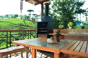 une table en bois avec un poêle sur une terrasse dans l'établissement Linda vista para as montanhas a 5 min da cidade, à Santo Antônio do Pinhal