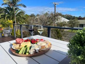 a plate of food on a table with a glass of wine at Family Tides - Old Bar Holiday Rentals in Old Bar