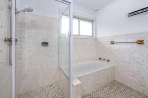 a bathroom with a shower and a bath tub at Family Tides - Old Bar Holiday Rentals in Old Bar +22 photos