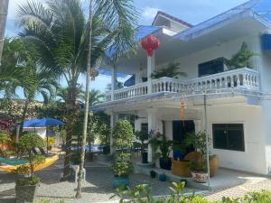 a white building with palm trees in front of it at Villa Blue Lagoon in Sihanoukville