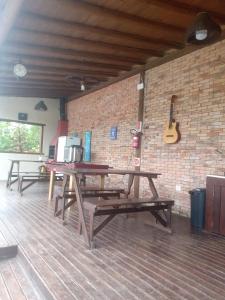 two picnic tables in a room with a brick wall at Cabanas Alamanda do Rosa in Imbituba +41 photos