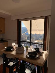einen Tisch mit Tellern und Weingläsern sowie ein Fenster in der Unterkunft Moment Collector in Ourense