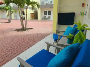 eine Terrasse mit blauen Stühlen und Palmen in einem Gebäude in der Unterkunft Aruba Condo The Pearl - At Eagle Beach - minute walk! in Palm-Eagle Beach
