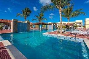 een zwembad met blauw water en palmbomen bij Aruba Condo The Pearl - At Eagle Beach - minute walk! in Palm-Eagle Beach
