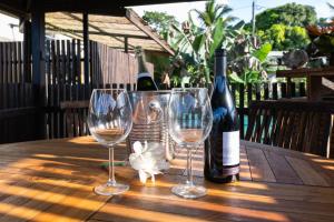 una mesa con dos copas y dos botellas de vino en KIA ORA LODGE en Afaahiti