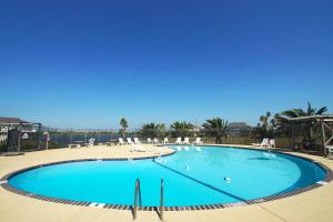 een groot blauw zwembad met stoelen en een strand bij Seaward Breeze in Galveston