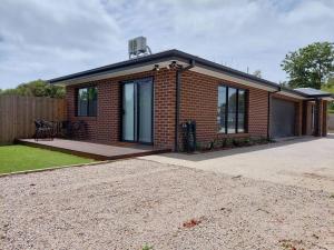 a small brick house with a driveway in front of it at Lake and Railway Guesthouse in Drysdale