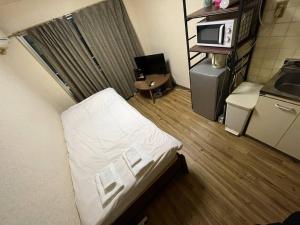 大阪市にあるアベニュー天神ノ森103 　Avenue Tenjinnomori 103のベッド1台、電子レンジが備わる小さな客室です。