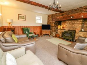 a living room with couches and a stone fireplace at Tanyrallt Farm in Beulah