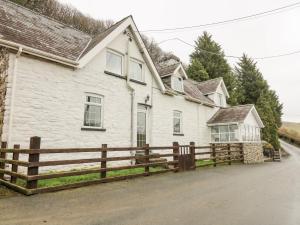 a white house with a wooden fence in front of it at Tanyrallt Farm in Beulah