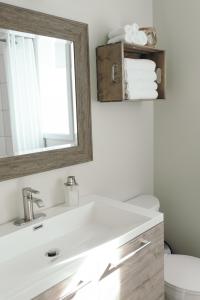 uma casa de banho com um lavatório branco e um espelho. em Le Contemporain em Rouyn