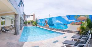 una piscina con sillas y un mural en un edificio en Hotel Savilayo en Ica