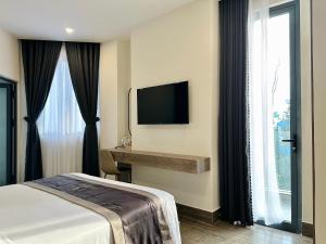 a hotel room with a bed and a desk and a television at LION 5 HOTEL in Can Tho
