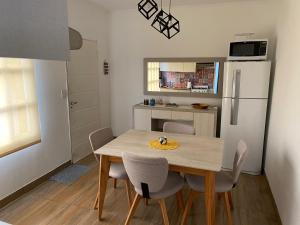 a kitchen with a table with chairs and a refrigerator at Apartamento Céntrico, Moderno y Tranquilo in Caleta Olivia