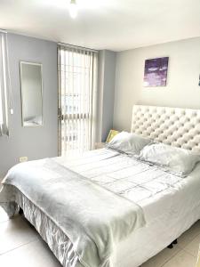 1 cama blanca grande en un dormitorio con ventana en Hermoso apartaestudio moderno valle de atriz norte, en Pasto
