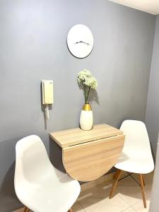 una mesa con dos sillas blancas y un reloj en la pared en Hermoso apartaestudio moderno valle de atriz norte, en Pasto