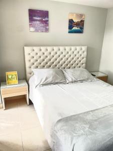 1 dormitorio con 1 cama blanca grande y 2 mesas en Hermoso apartaestudio moderno valle de atriz norte, en Pasto