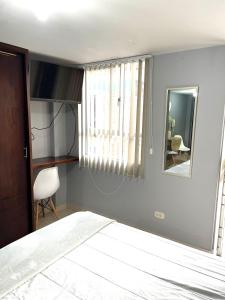 1 dormitorio con cama, espejo y silla en Hermoso apartaestudio moderno valle de atriz norte, en Pasto