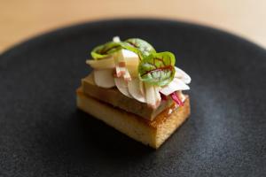 a piece of food sitting on a black plate at Yoichi LOOP in Kurokawamachi