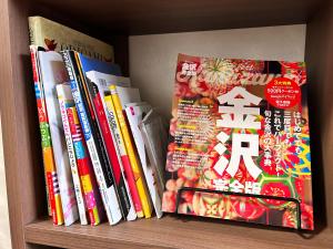 un estante lleno de libros en una pared en 旅籠屋ゆいまーる, en Mameda-shimmachi