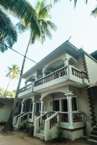 a house with a balcony and a palm tree at Jolene's Ashvem in Mandrem