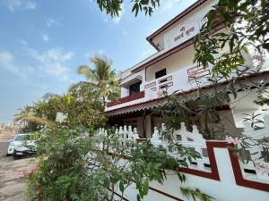 un edificio blanco con árboles delante de él en Gayatri Homestay en Ratnagiri