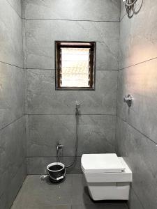uma casa de banho com um WC e uma janela em Gayatri Homestay em Ratnagiri