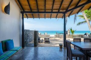 eine Terrasse mit Tisch und Stühlen sowie Strand in der Unterkunft Blue Parrot Beach Villa in Ambalangoda