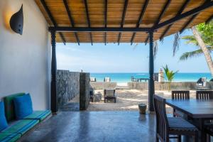 a patio with a table and chairs and the beach at Blue Parrot Beach Villa in Ambalangoda