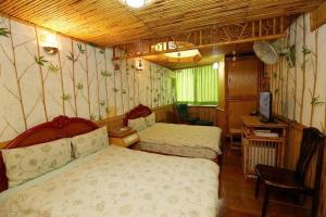 信義鄉的住宿－玉山樓民宿，一间卧室配有两张床、一张桌子和一台电视。