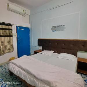 a bedroom with a bed and a blue door at Nest Tales Backpacker Hostel in Khajurāho