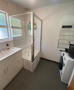 a bathroom with a shower and a washing machine at Coningham Beach House in Coningham