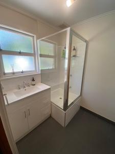 a bathroom with a shower and a sink and a mirror at Coningham Beach House in Coningham
