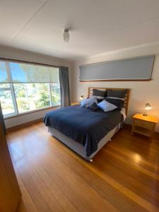 a bedroom with a bed and a large window at Coningham Beach House in Coningham
