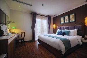een hotelkamer met een groot bed en een bureau bij Hotel Emerald Waters Classy in Hanoi
