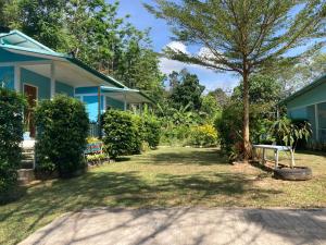 une cour à côté d'une maison bleue avec un arbre dans l'établissement Baan seefa homestay kohyaoyai, à Ko Yao Yai