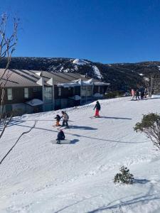 a group of people skiing down a snow covered slope at Woodsmoke Two Falls Creek in Falls Creek