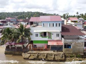 a white house with a red roof next to the water at Nasional Hotel in Gunungsitoli
