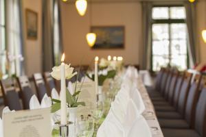 Una mesa larga con velas blancas y flores. en Pension und Schänke Lenzer Krug, en Lenz