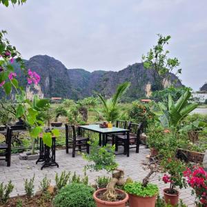 a patio with a table and chairs with mountains in the background at Amazing View Homestay in Ninh Binh