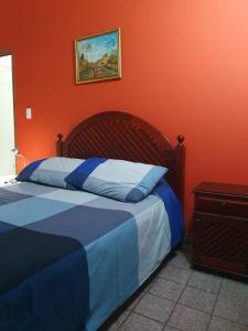 1 dormitorio con 1 cama con pared de color naranja en Dúplex La Nona en Salta