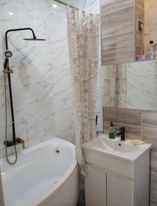 een badkamer met een wit bad en een wastafel bij студия Вефа in Bisjkek