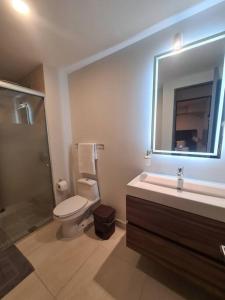 a bathroom with a toilet and a sink and a mirror at Departamento con vista increíble en piso 16 in Guadalajara