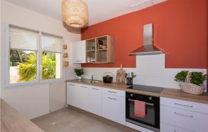 uma cozinha com armários brancos e uma parede laranja em Gorgeous Home In Poulx With Wifi em Poulx