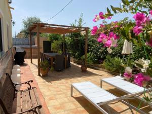 un patio con 2 bancos, una mesa y flores en Casa La Madriguera, en El Verger