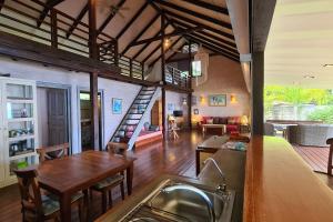 uma cozinha e sala de estar com uma escada numa casa em Cottage Miti Reva em Haapiti