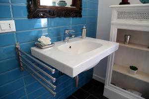 La salle de bains est pourvue d'un lavabo blanc et de carrelage bleu. dans l'établissement Nido Degli Angeli, à Rome