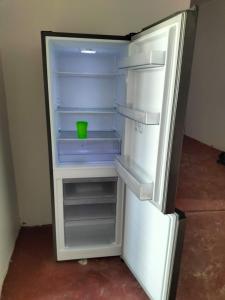 an empty refrigerator with a green bowl inside of it at Mambo Leo Hostel in Paje