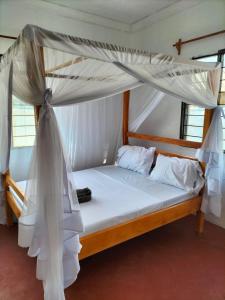 a bed with a canopy in a room at Mambo Leo Hostel in Paje