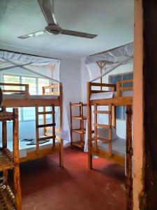 two bunk beds in a room with a ceiling at Mambo Leo Hostel in Paje